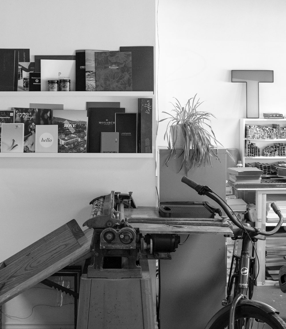 Charm and Gusto Studio black and white photo of shelves, folding machine, and bike