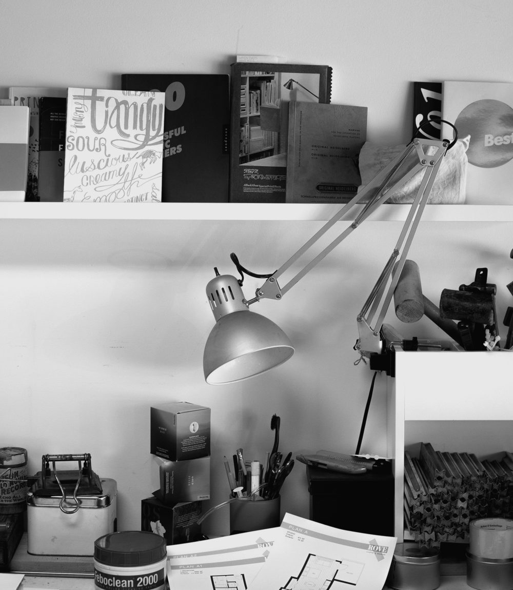 Charm and Gusto studio black and white photo of desk, lamp, shelves and tools